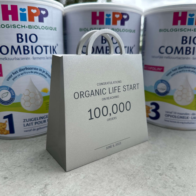 A gift bag congratulating Organic Life Start on 100,000 orders, in front of HiPP formula tins